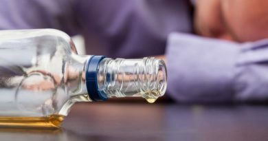 Drunk man sleeping with almost empty bottle of alcohol